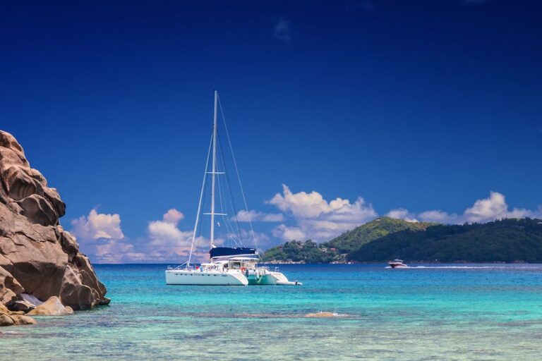 Crewed sailing catamaran at anchor over shallow turquoise water