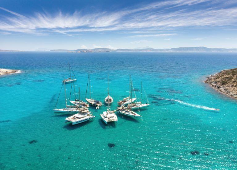 Aerial view of sailing yachts gathered in a star formation off Polyaigos, in the Cyclades