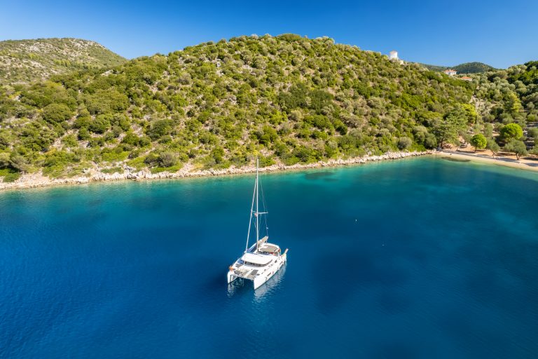 A catamaran moored in a turquoise bay near Dexia beach on Ithaca, in the Ionian