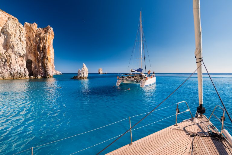 Yachts at anchor in turquoise water off the south coast of Polyaigos, near Milos, in the Cyclades