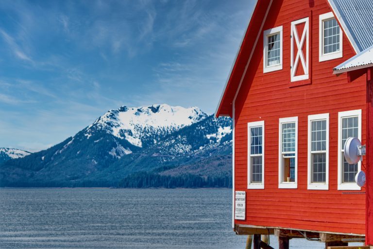 Red dockside building on Icy Strait with snow-capped mountains, Alaska